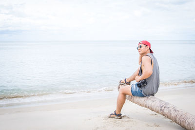 Young woman wearing sunglasses on beach against sky