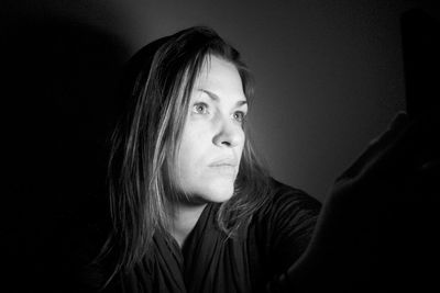 Close-up of woman looking away over black background