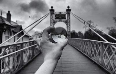 Close-up of woman hand on footbridge against sky