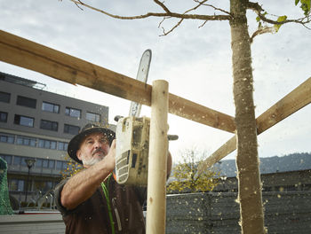 Mature gardener building fence around freshly planted tree