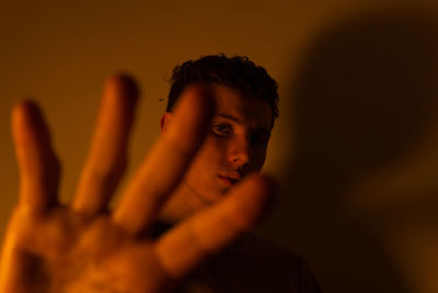 Close-up portrait of young man against orange background