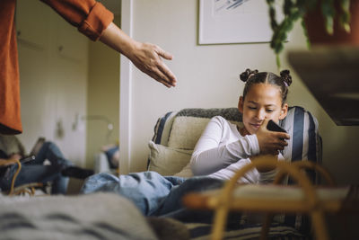 Daughter ignoring father while using mobile phone at home