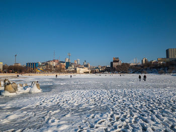 Surface level of snow covered land against clear blue sky