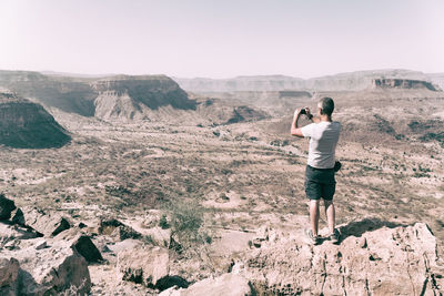 Rear view of man photographing on mountain