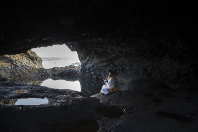 Rear view of man standing on rock cave