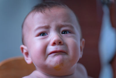 Close-up of cute baby boy crying at home