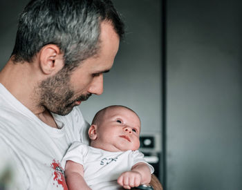 Dad holding baby son indoor in room at home