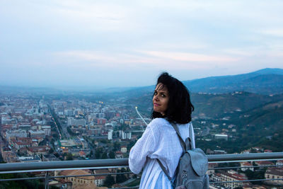 Portrait of young woman against cityscape