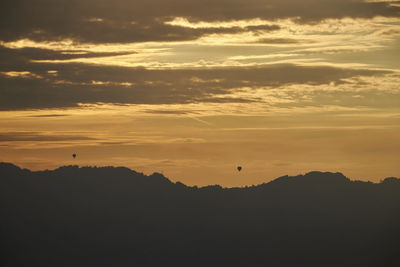 Silhouette of birds flying in sky during sunset