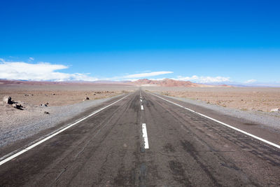 View of road amidst desert against blue sky