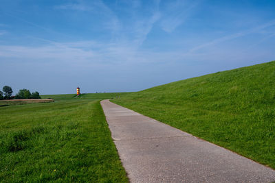 Road amidst field against sky