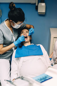 Dentist operating pregnant woman in medical clinic