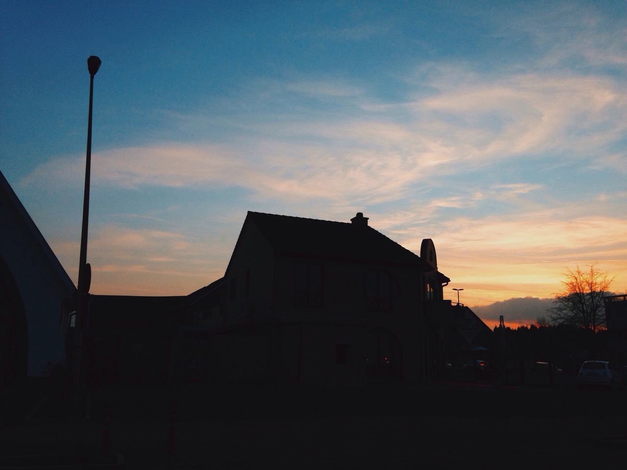 building exterior, sunset, architecture, built structure, sky, street light, silhouette, transportation, low angle view, cloud - sky, car, street, orange color, land vehicle, dusk, cloud, mode of transport, outdoors, city, building