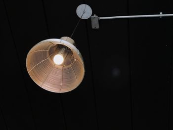 Low angle view of illuminated light bulb hanging from ceiling