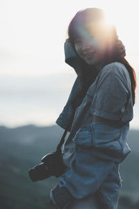 Portrait of smiling woman standing against sky during sunset