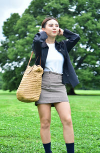 Portrait of young woman standing against trees