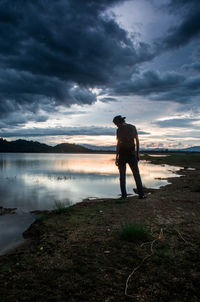 Rear view of man photographing lake against sky