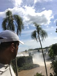 Portrait of man by palm trees against sky