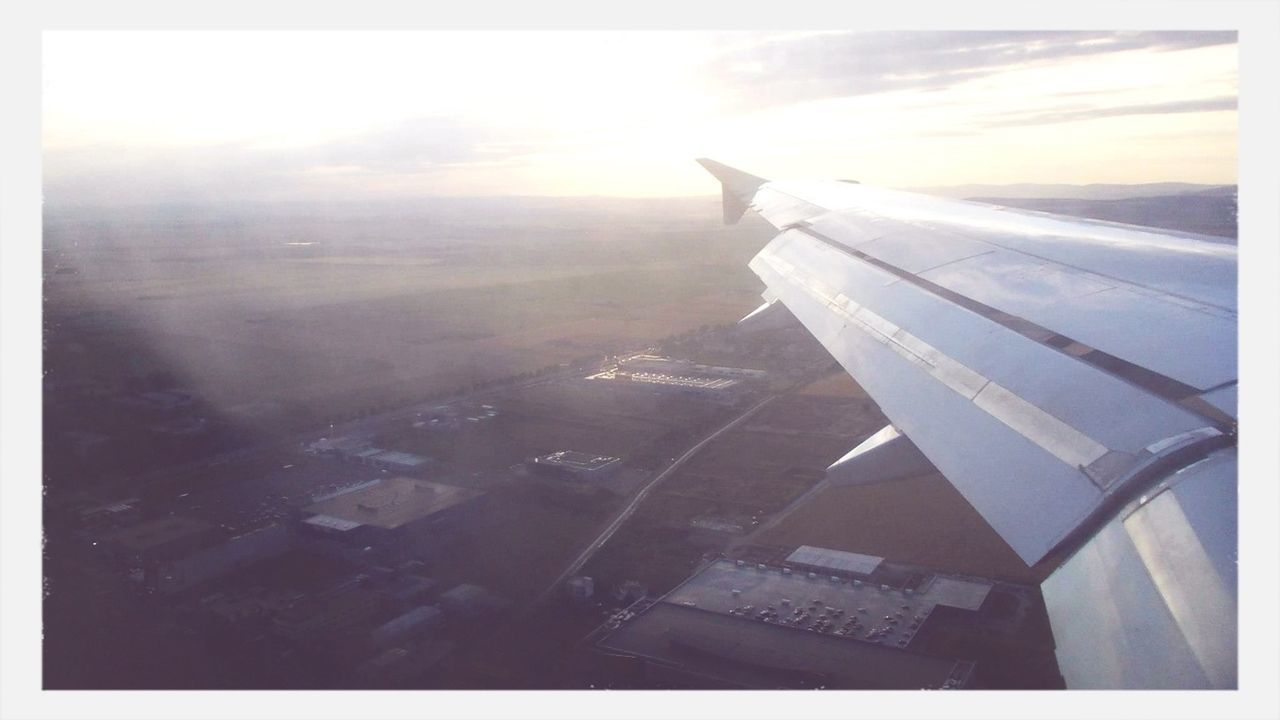 airplane, aircraft wing, transportation, air vehicle, aerial view, sky, mode of transport, flying, cropped, part of, landscape, travel, on the move, cloud - sky, journey, sunlight, scenics, sun, nature, window