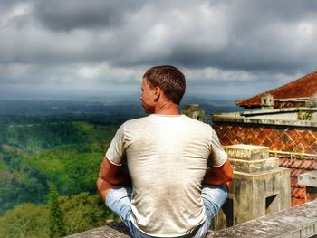 Rear view of man looking at mountains against sky