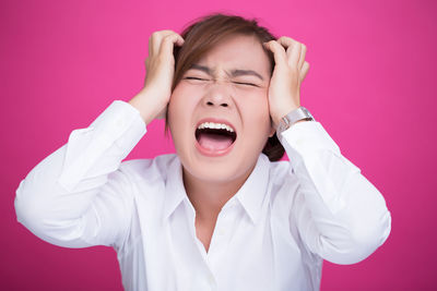 Portrait of mid adult woman against pink background