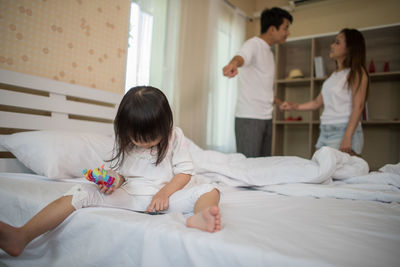 Girl watching video in mobile phone while parents arguing at home