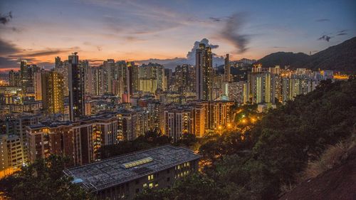 Illuminated cityscape against sky during sunset