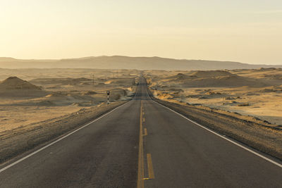 Empty road along landscape and mountains against sky