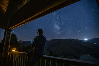 Rear view of man looking at sky at night