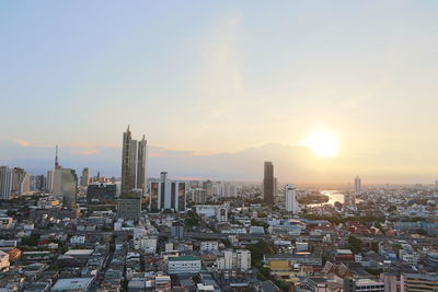 Aerial view of buildings in city against sky during sunset