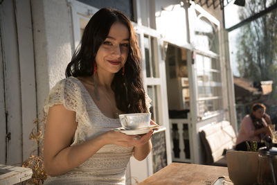 Portrait of smiling young woman holding drink