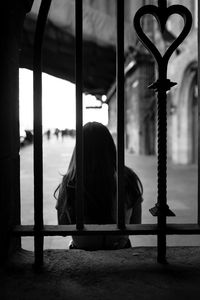 Rear view of woman sitting against built structure