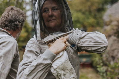 Woman putting beekeepers suit on