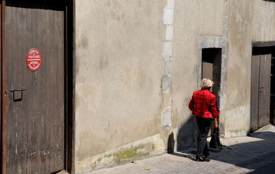 Rear view of woman walking on sidewalk in city