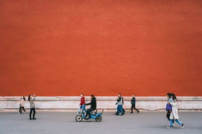People on bicycle against wall in city