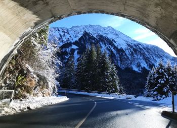 Snow covered road by trees against sky