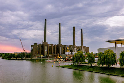 Buildings by river against sky in city