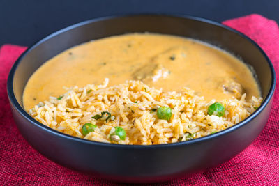 Close-up of rice with curry in bowl against black background