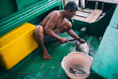 High angle view of shirtless man sitting in water