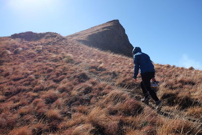 Rear view of man walking on mountain against sky