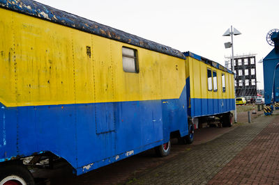 Old travel trailers parked on street against clear sky