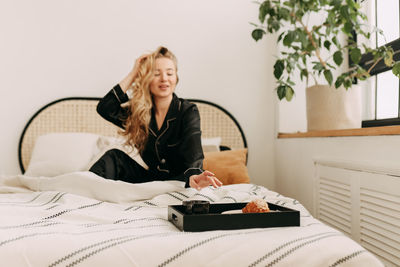 Young woman using mobile phone on bed at home