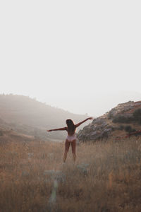 Rear view of man with arms outstretched against clear sky