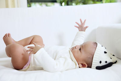 Close-up of baby girl lying on bed