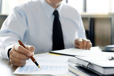 Midsection of man holding paper