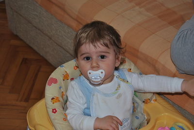 Portrait of cute baby boy sucking pacifier at home