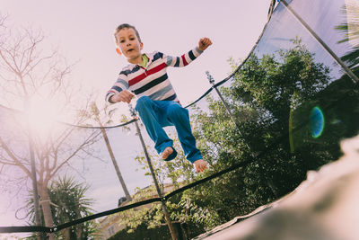 Low angle view of boy jumping on trampoline