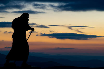 Side view of silhouette man standing against sky during sunset