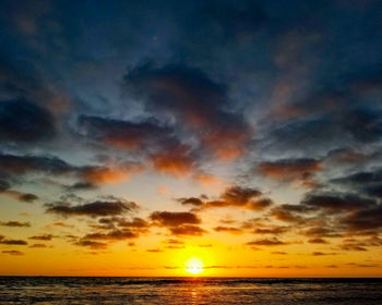 Scenic view of sea against dramatic sky during sunset