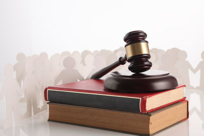 High angle view of hammer and gavel with books and paper chains against white background